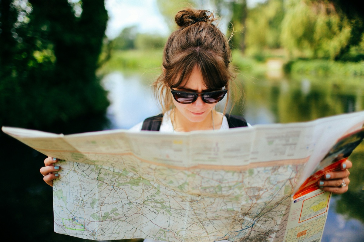 A traveler reading a paper map by a river