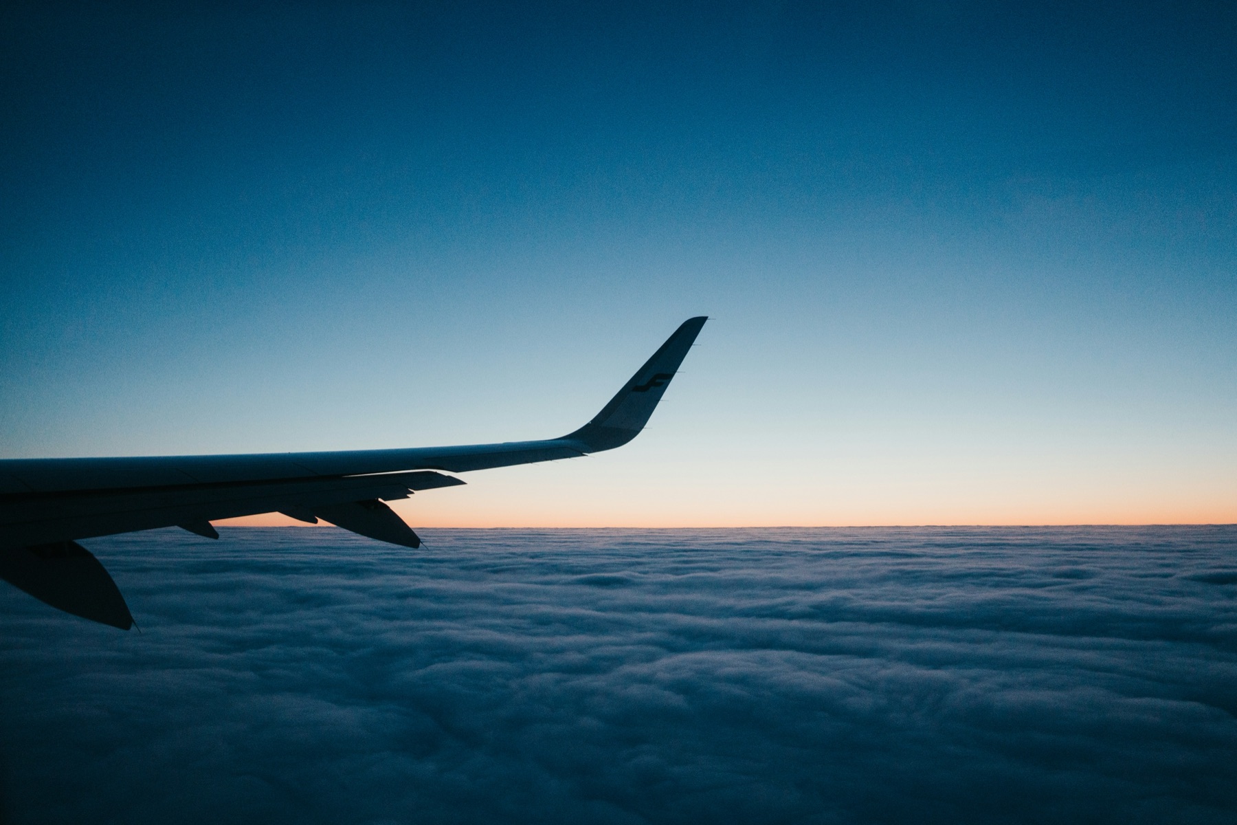 Airplane wing above the clouds at dusk
